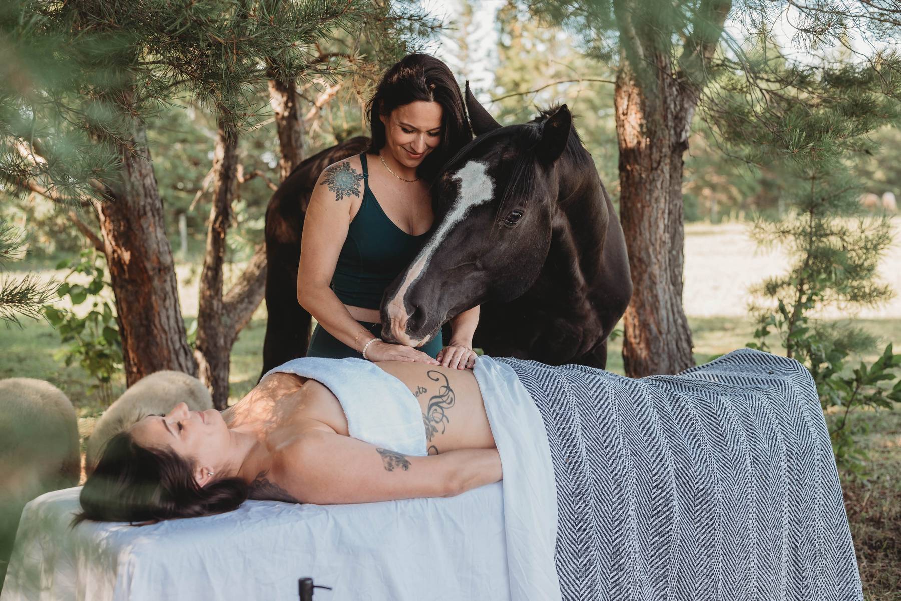 Therapist performing a lymphatic drainage massage on a client's abdomen outdoors